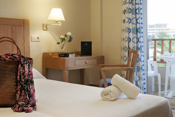 Ein ruhiges Hotelzimmer im Voramar Formentera mit einem Bett, einem Stuhl, einem Tisch und Blick auf den Balkon.