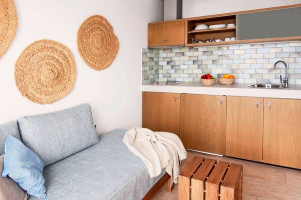 Die Küche und Schlafbereich des Castavi Hotels mit einer Couch, einem Holzhocker, einer modernen Küche und drei Wandkörben.