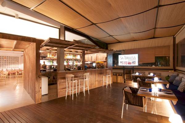 Innenansicht des Castavi Hotels mit der Bar Sa Terrassa, Holzboden, modernen Stühlen und Tischen.