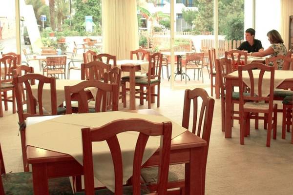 Innenbereich des Roca Plana Hotels mit mehreren Tischen und Stühlen, zwei Personen sitzen und unterhalten sich.
