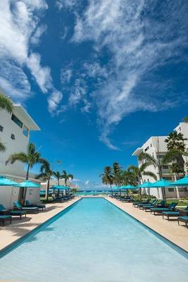 Außenpool mit Sonnenliegen und blauen Sonnenschirmen im Hotel The Sands Barbados.
