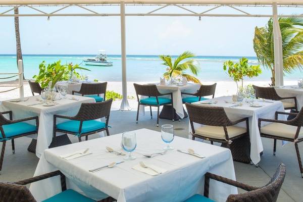 Außenbereich des Sands Barbados Hotels mit Tischen und Stühlen, Blick auf das Meer.