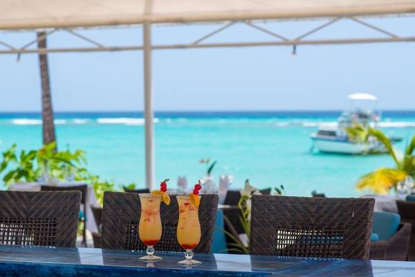 Cocktails auf der Terrasse des The Sands Barbados am Strand mit Blick auf das Meer und ein Boot.