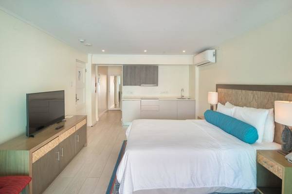Schlafzimmer im The Sands Barbados Hotel mit großem Bett, Fernseher und Küche