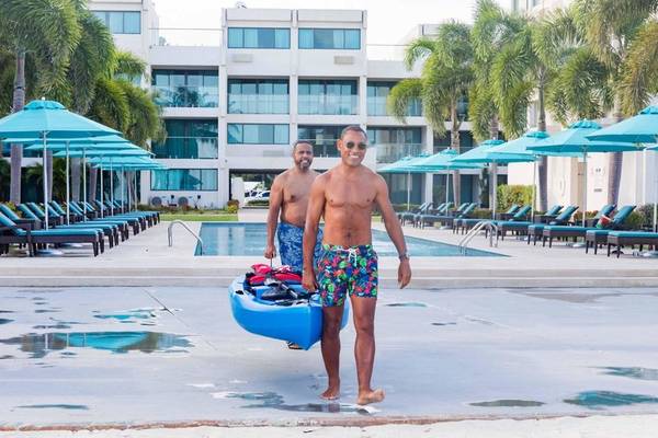 Zwei Männer tragen ein Kajak am Poolbereich des Sands Barbados Hotels.