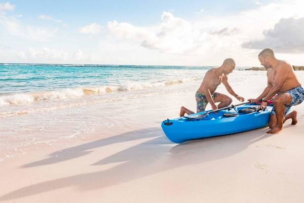 Zwei Männer am Strand von Sands Barbados, die ein blaues Kajak vorbereiten.