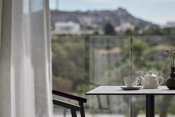 Blick aus einem Zimmer im Helea Lifestyle Beach Resort auf einen Tisch mit Teekanne, Tasse, Untertasse und Vase mit Blumen.