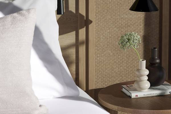 Ein Bett mit Tisch und Blumen im Schlafzimmer, die Nachttischlampe hängt von der Decke.