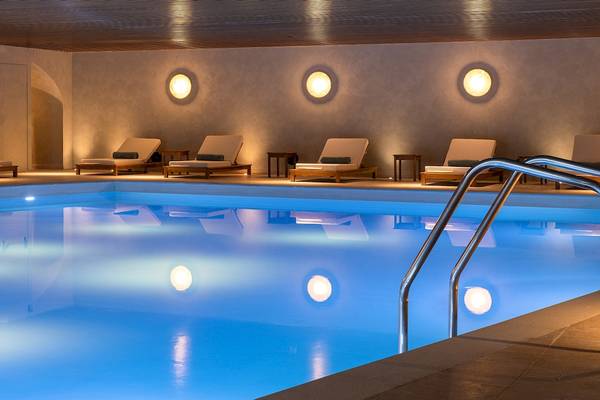Pool-Loungebereich im Helea Lifestyle Beach Resort mit beleuchteten Wänden und Loungestühlen.