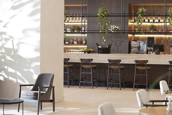Barbereich im Helea Lifestyle Beach Resort mit gepolsterten Stühlen und Theke.