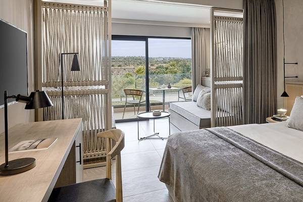 Innenansicht eines Hotelzimmers im Helea Lifestyle Beach Resort mit großem Bett, Schreibtisch und Aussicht.