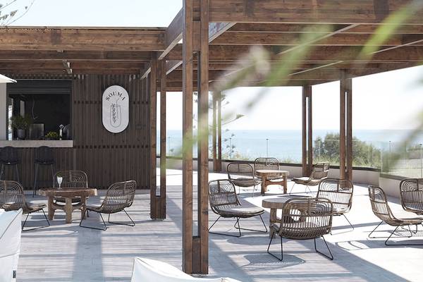 Außenbereich der Helea Lifestyle Beach Resort Bar mit Holzmöbeln und Meerblick.
