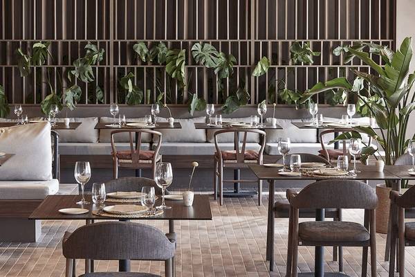 Innenansicht des Restaurants im Helea Lifestyle Beach Resort mit gedeckten Tischen und grünen Pflanzen.