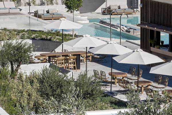 Aussicht auf die Terrasse des Helea Lifestyle Beach Resorts mit Tischen, Stühlen und Sonnenschirmen.