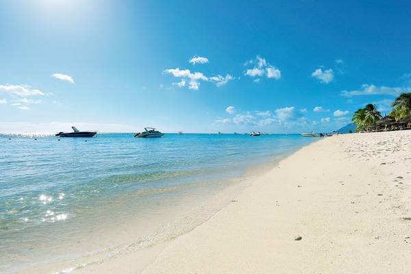 Strand des Paradis Beachcomber Golf Resort & Spa mit Booten im Wasser und blauem Himmel