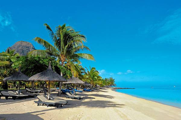 Strand des Paradis Beachcomber Golf Resort & Spa mit Sonnenliegen und Palmen