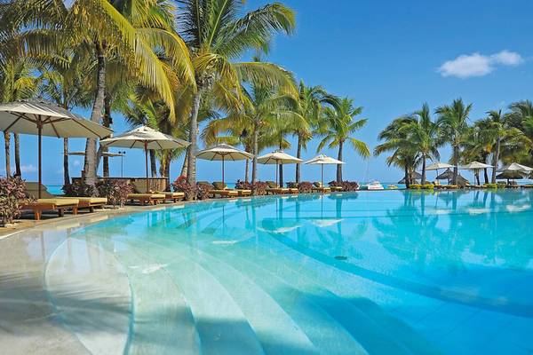 Ein großer Pool mit Liegestühlen und Sonnenschirmen im Paradis Beachcomber Golf Resort.