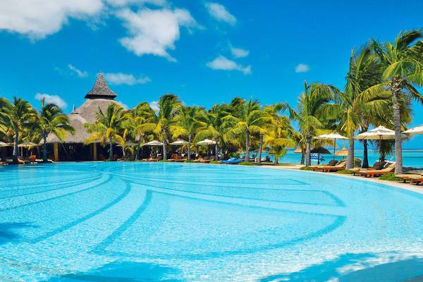 Außenpool des Paradis Beachcomber Golf Resort & Spa mit tropischen Palmen und Sonnenliegen.