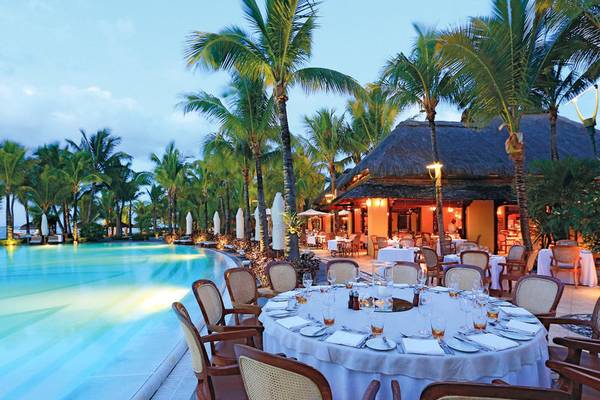 Außenbereich des Paradis Beachcomber Golf Resort & Spa mit einem großen Pool und einem Essbereich im Freien.