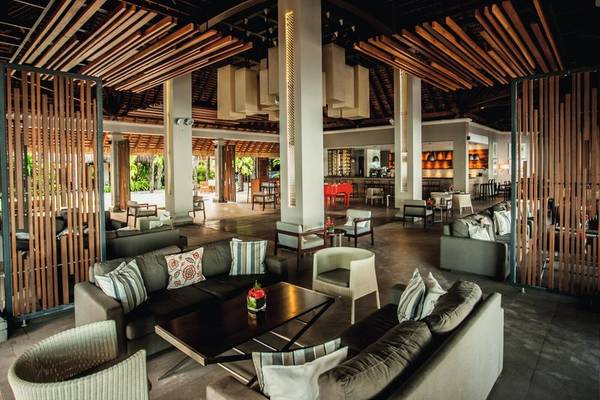Innenbereich des Paradis Beachcomber Golf Resort & Spa mit Sofas, Tischen und Holzelementen.