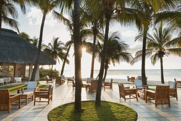 Außenterrasse des Paradis Beachcomber Golf Resort & Spa mit Palmen und Stühlen