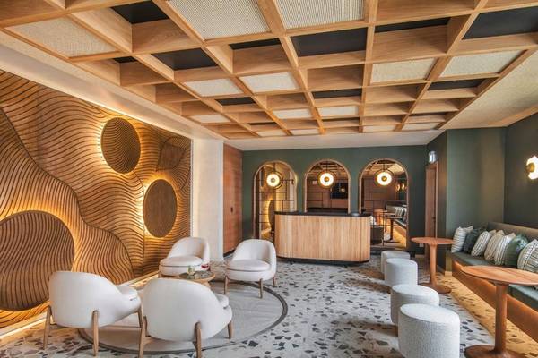 Loungebereich im Paradis Beachcomber Golf Resort & Spa mit weißen Sesseln, Holzelementen und grünen Wänden.