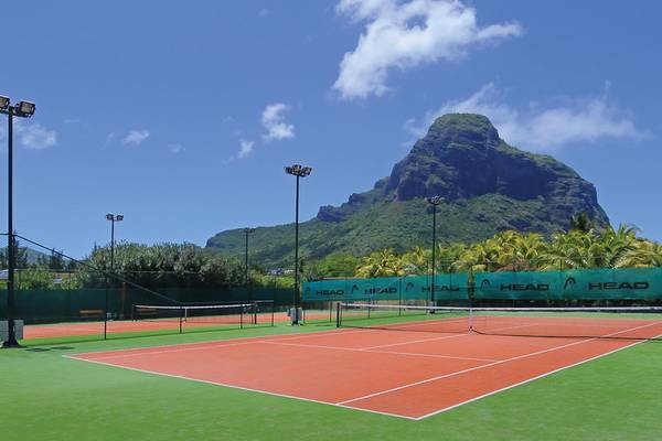 Tennisplatz im Paradis Beachcomber Golf Resort & Spa mit grünem Platz und orangefarbenen Linien.