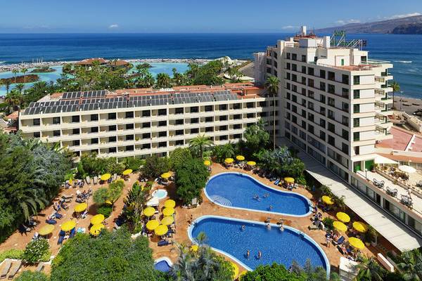 H10 Tenerife Playa Hotel Außenbereich mit Swimmingpools und Sonnenschirmen.