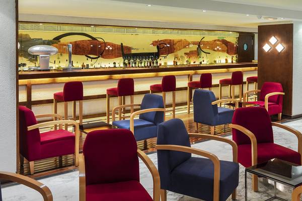 Innenansicht der Bar im H10 Tenerife Playa Hotel mit roten und blauen Stühlen.