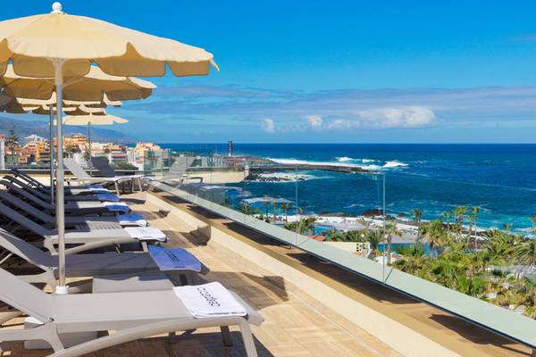 Terrasse des H10 Tenerife Playa Hotels mit Sonnenliegen und Blick auf das Meer.
