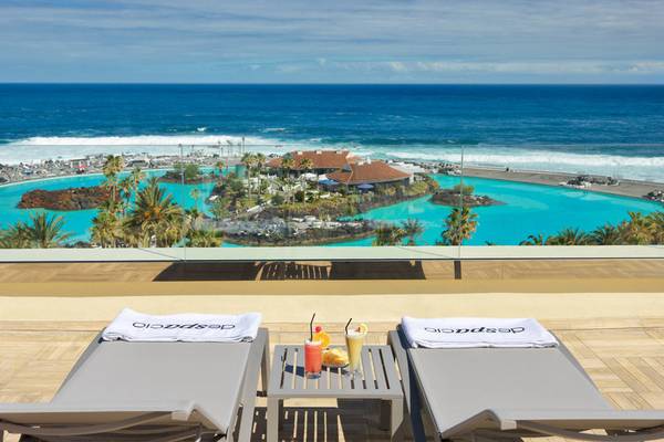 Terrasse im H10 Tenerife Playa Hotel mit Blick auf einen Pool und das Meer.