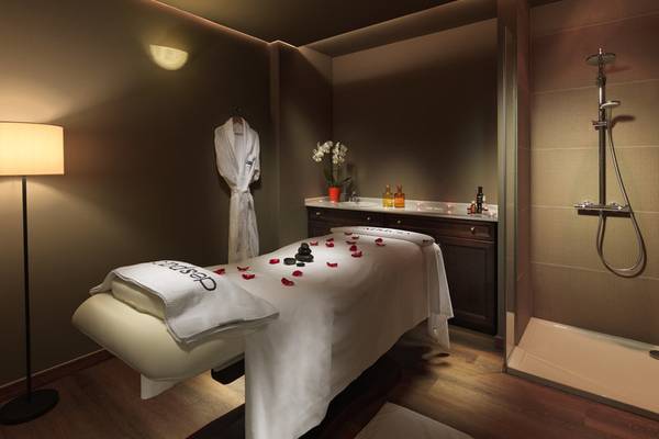 Spa-Behandlungsraum im H10 Tenerife Playa mit einem Behandlungsbett, einem Bademantel, einer Dusche und einer Lampe.