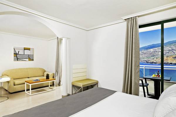 Innenansicht eines Zimmers im H10 Tenerife Playa Hotel mit Blick auf das Meer.
