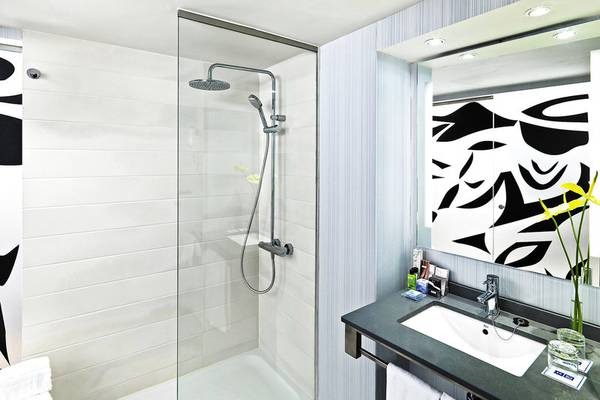 Badezimmer im H10 Tenerife Playa Hotel mit Glasdusche, Waschbecken und großer Spiegel.
