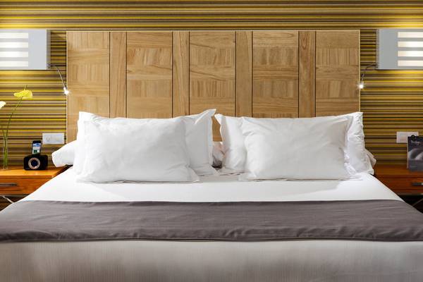 Bett im H10 Tenerife Playa Hotel mit weißen Kissen und braunem Kopfteil