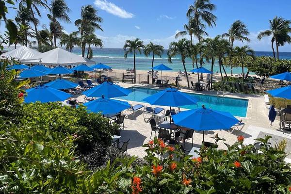 Außenbereich des Coconut Court Beach Hotels mit Pool, Sonnenschirmen und Blick auf den Strand