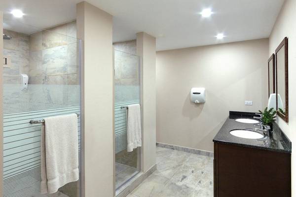 Badezimmer im Coconut Court Beach Hotel mit Glasdusche und Waschbecken.