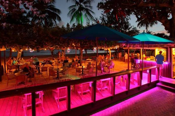 Terrasse des Coconut Court Beach Hotels bei Nacht mit beleuchteten Tischen und Stühlen