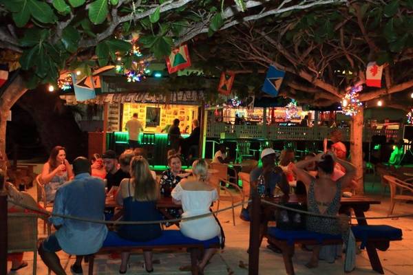 Terrasse des Coconut Court Beach Hotels bei Nacht mit Gästen an Tischen und Dekoration.