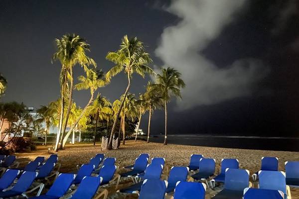 Nachtansicht des Coconut Court Beach mit blauen Sonnenliegen und Palmen