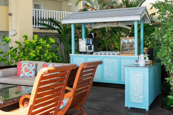 Café-Sitzecke im Freien im Sugar Bay Barbados Hotel mit blauem Stand und Holzstühlen.