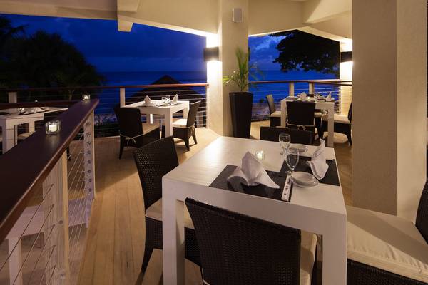 Terrasse des Sugar Bay Barbados Hotels mit Tischen und Stühlen und Blick auf den Ozean