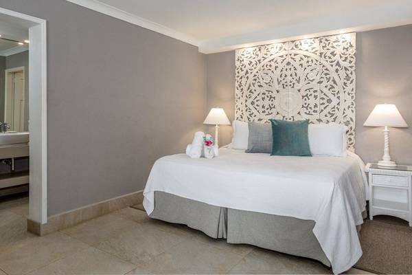 Schlafzimmer im Sugar Bay Barbados Hotel mit weißem Bett, dekorativem Kopfteil und zwei Nachttischen.