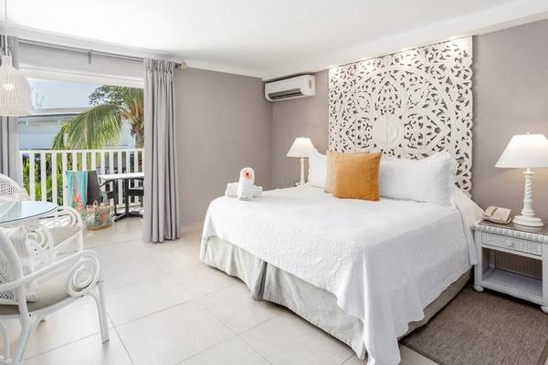 Ein elegantes Zimmer im Sugar Bay Barbados mit einem großen Bett, Klimaanlage und Balkon.