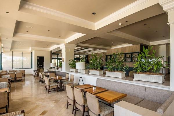 Innenbereich des Hilton Barbados Hotels mit Tischen, Stühlen und Pflanzen in weißen Tönen.