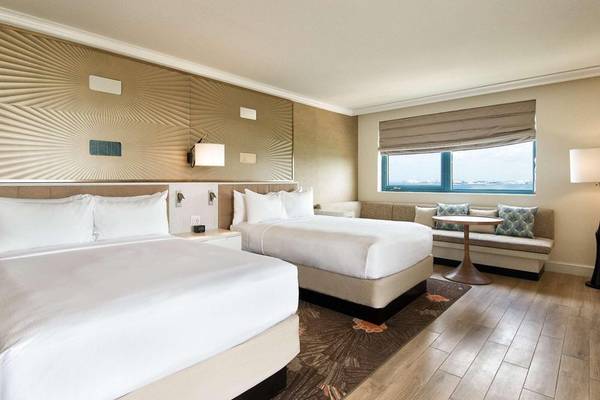 Doppelzimmer im Hilton Barbados mit zwei Betten, Couch, Tisch und Fenster mit Meerblick.