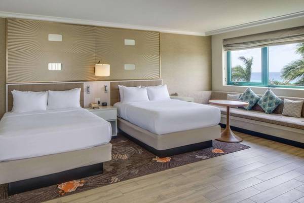 Doppelzimmer im Hilton Barbados mit zwei Betten, Couch, Tisch und Meerblick