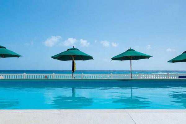 Ein Swimmingpool des Rostrevor Hotels mit grünen Sonnenschirmen und Blick auf das Meer.