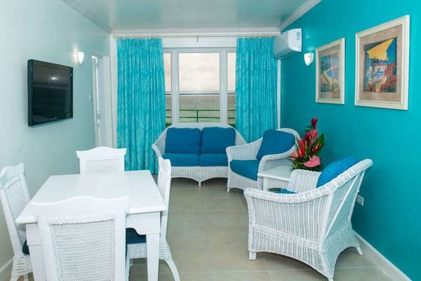 Wohnzimmer im Rostrevor Hotel mit blauen Wänden, weißen Möbeln, einem Fernseher und einem Blick auf das Meer.