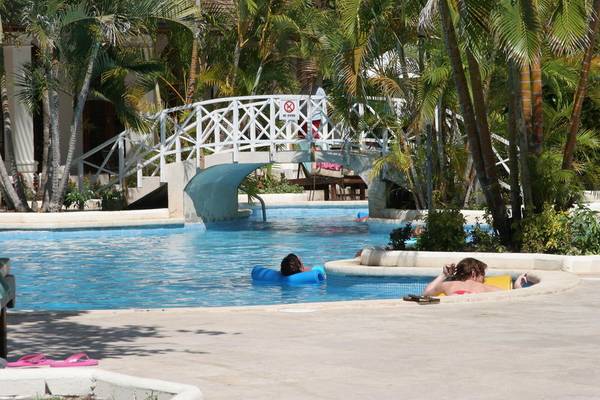 Am Mango Bay Hotel ein Pool mit Brücke und Palmen, Personen schwimmen